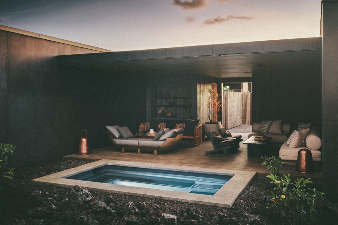 An outdoor patio with a private pool, lounge  chairs, and lanterns.